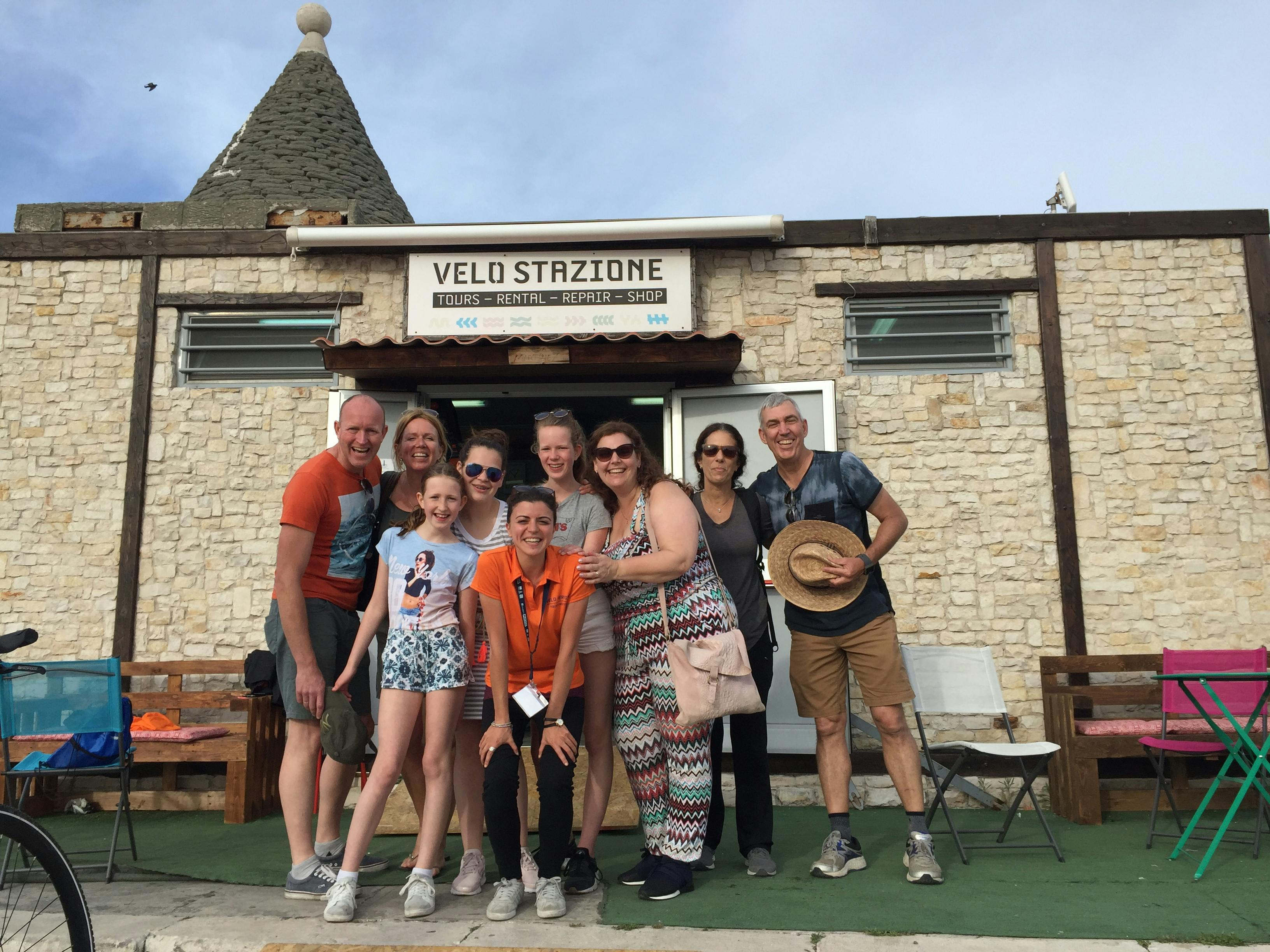 A group of nine people smiling in front of a building labeled 