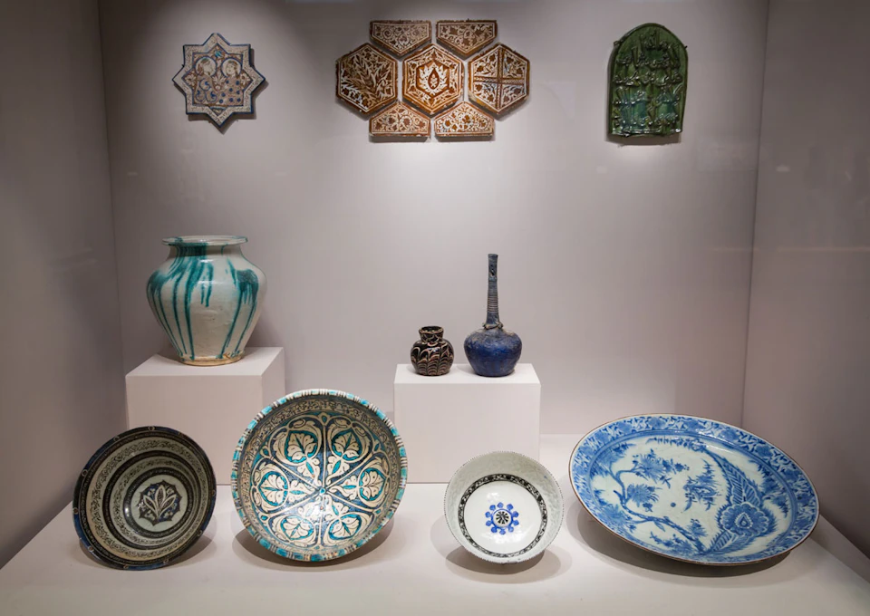 A display of various ceramic and pottery items, including bowls, vases, and tiles, each with intricate patterns and designs.