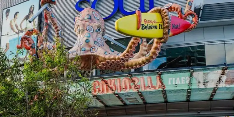 Una gran escultura de pop amb un cartell de "Ripley's Believe It or Not!" a la façana d'un edifici amb arbres en primer pla.