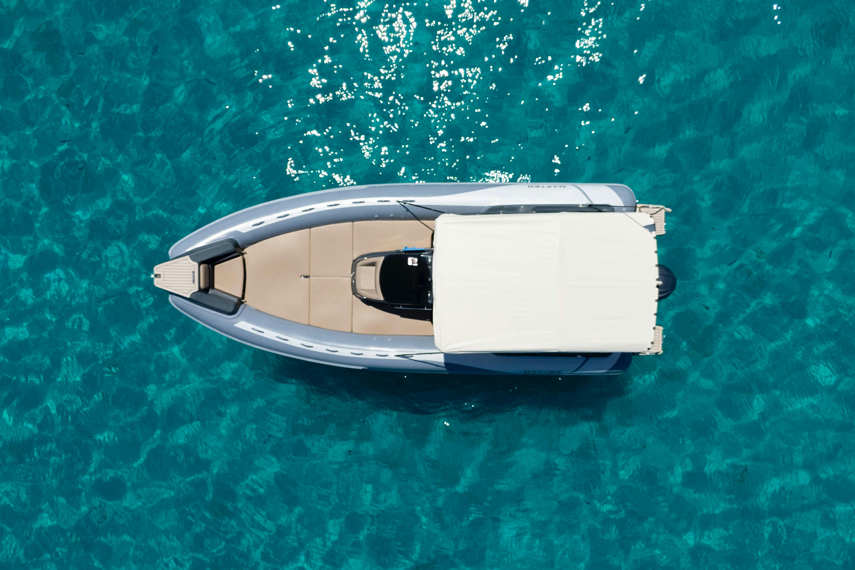 Vista dall'alto di un motoscafo con tettuccio bianco, fotografato su un'acqua limpida e blu.