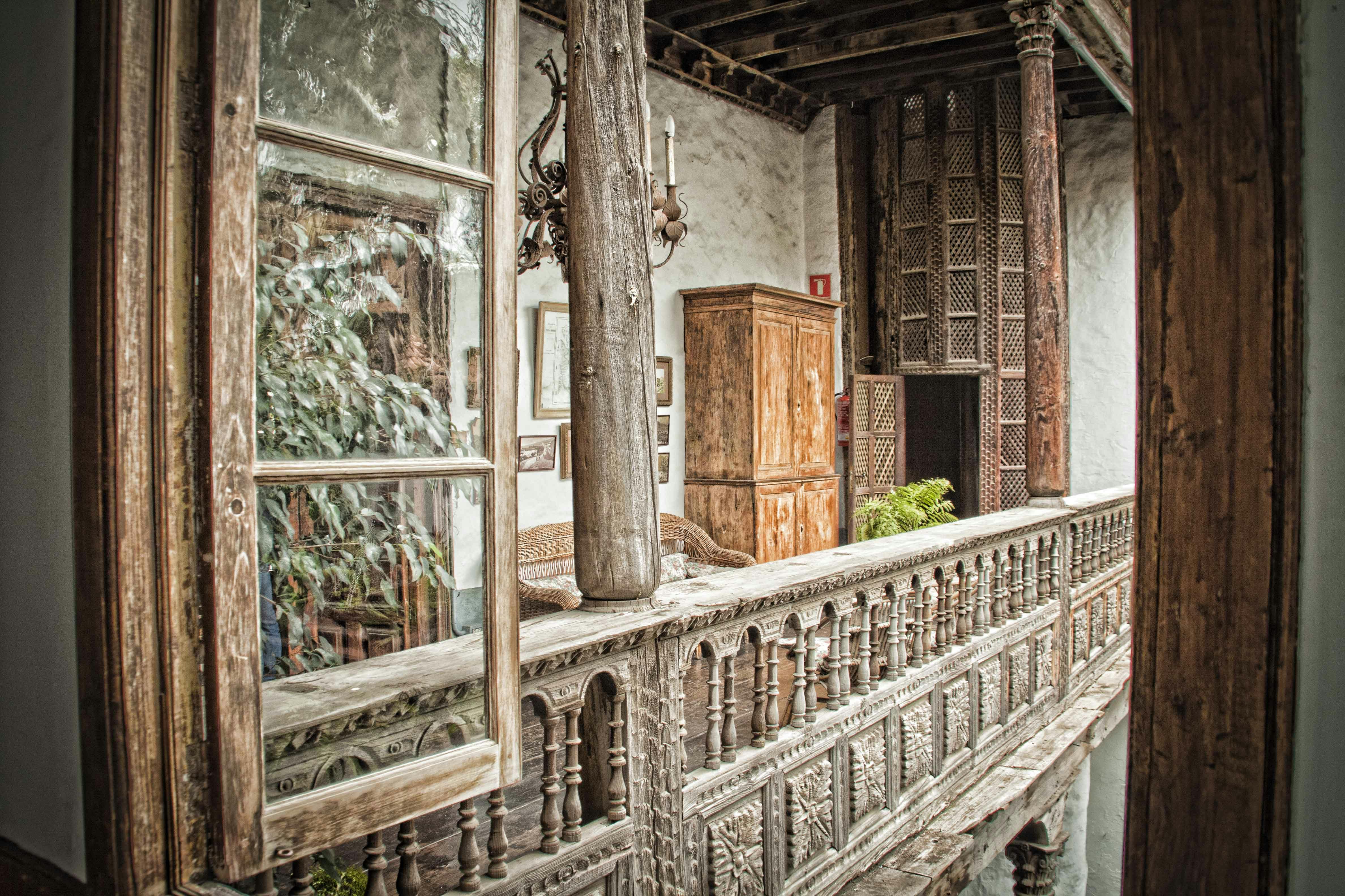 디테일한 난간, 소박한 가구, 화분, 빈티지한 분위기의 행잉 샹들리에가 있는 화려한 나무 발코니.