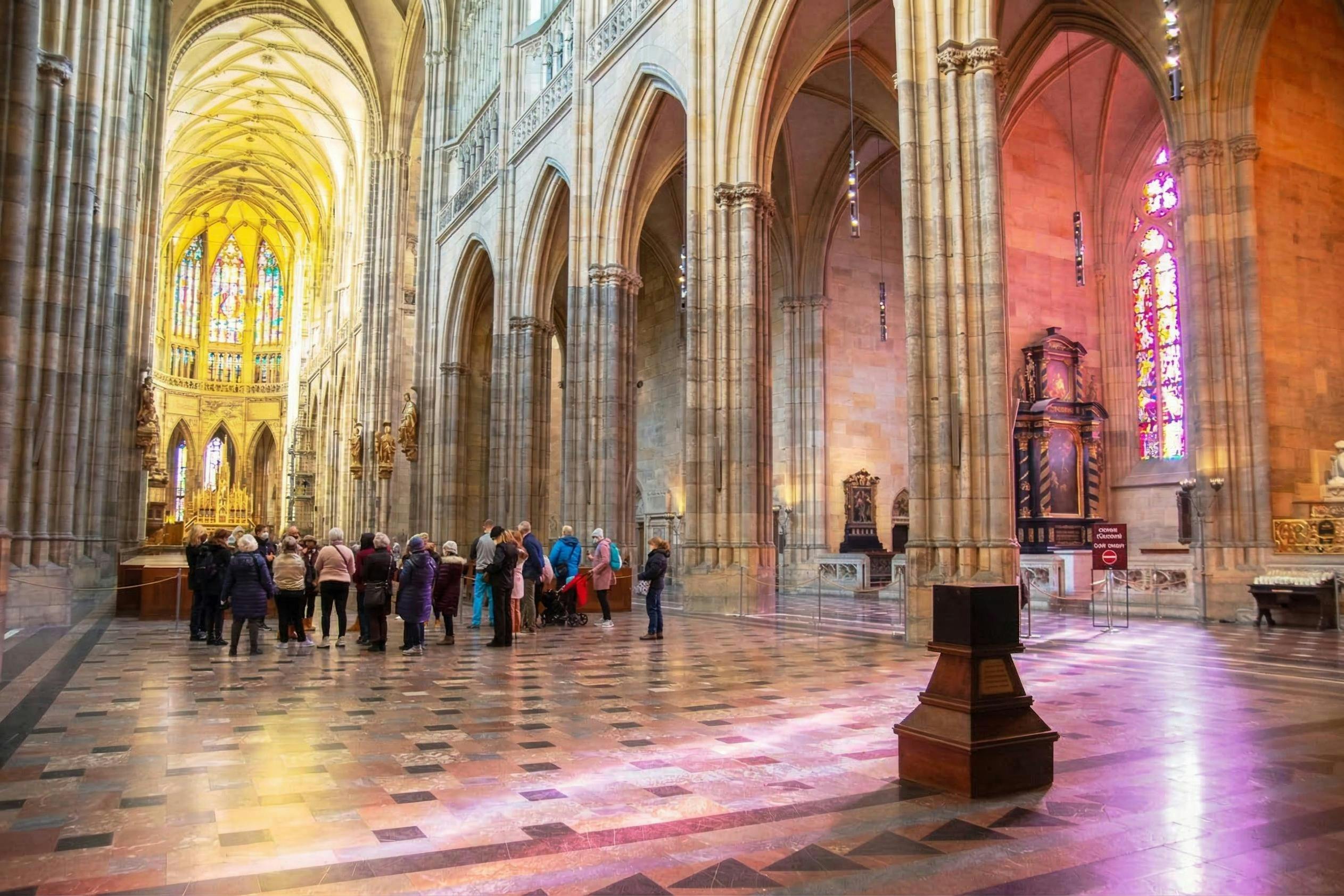A group of people touring the interior of a large cathedral with high ceilings, stained glass, and ornate architecture.