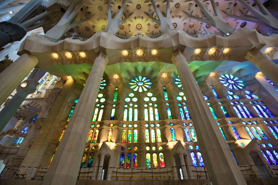 Interior of a cathedral with tall columns and colorful stained glass windows illuminating the space.
