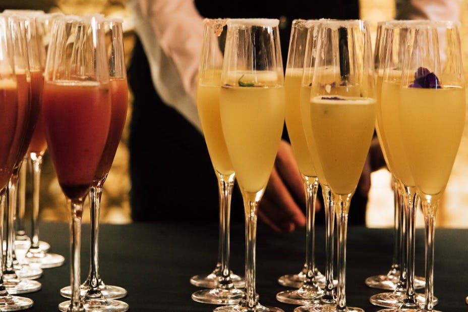 桌子上摆着一杯黄色和红色鸡尾酒，背景是一个穿着正式服装的人。