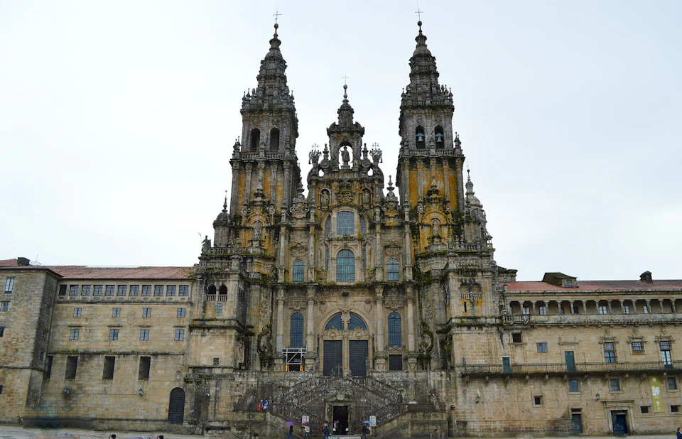 Historic cathedral with ornate facade, two tall towers, and multiple windows. People visible at the entrance at the bottom.
