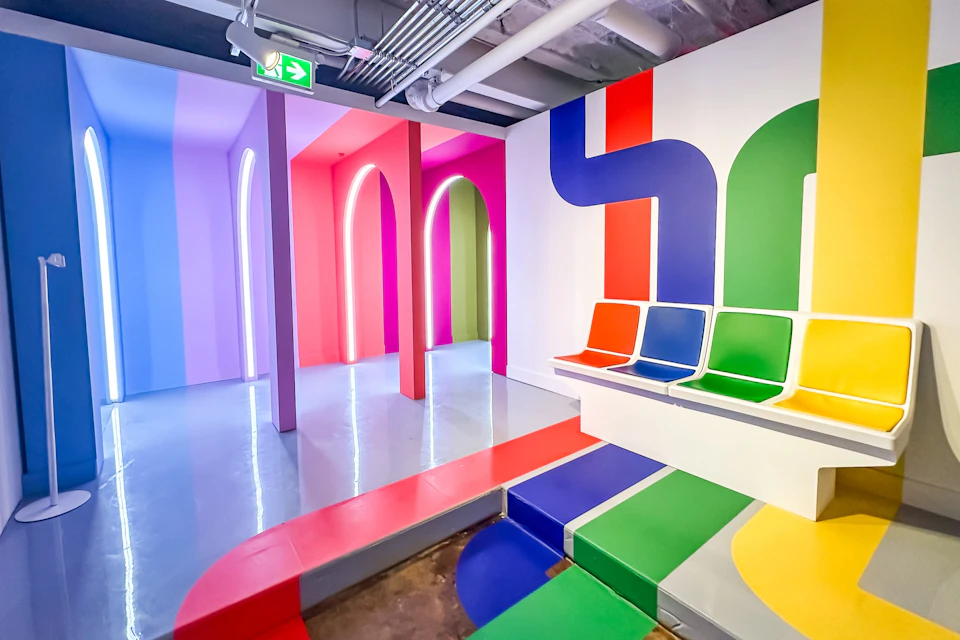 A colorful room with vibrant arches, multicolored seating, and a modern design featuring bold, curving lines on walls and floors.