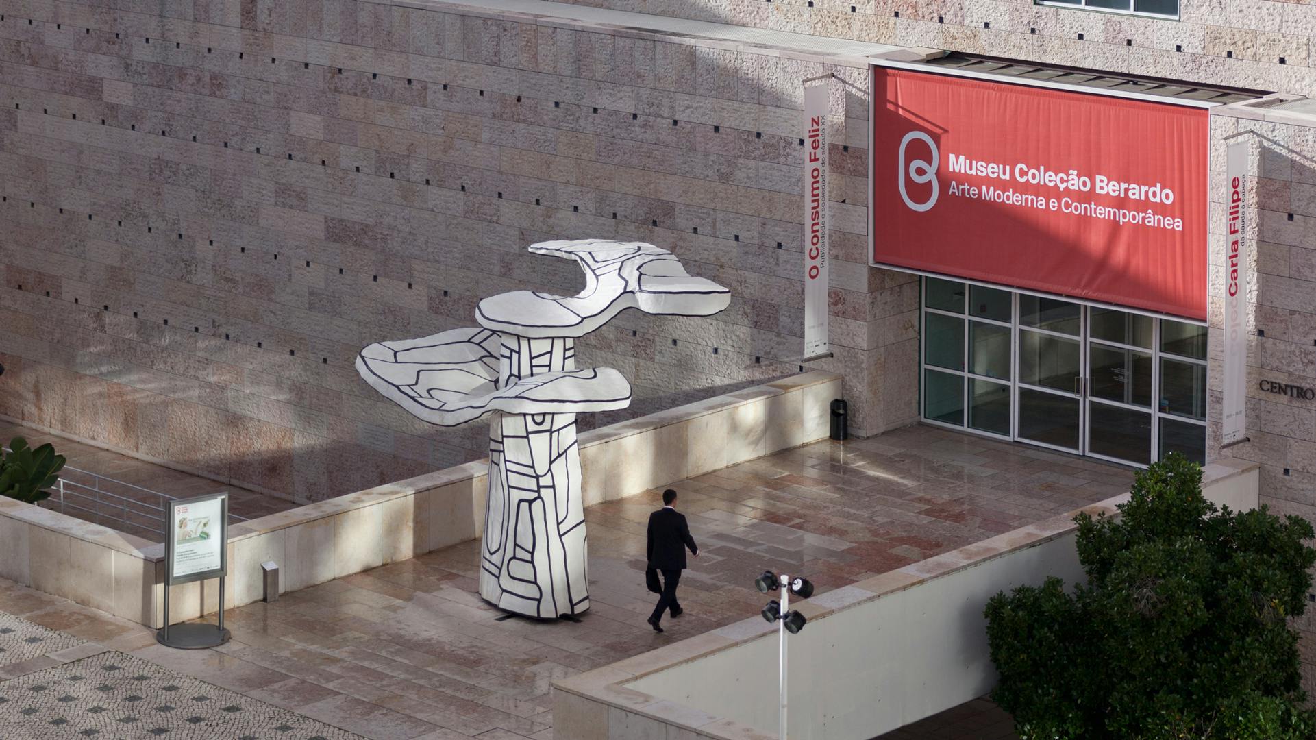 Un homme passe devant une œuvre d'art sculpturale à l'extérieur du Museu Coleção Berardo à Lisbonne, marquée d'un grand panneau rouge.