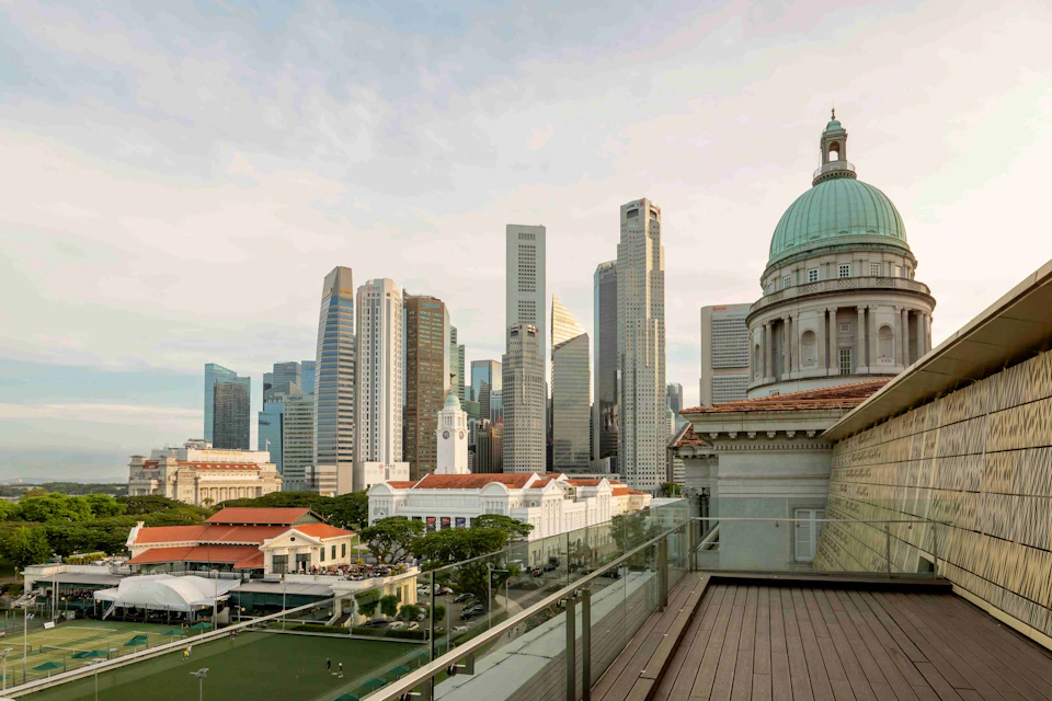 Skyline view with modern skyscrapers and historic buildings, including a domed structure in the foreground, under a partly cloudy sky.
