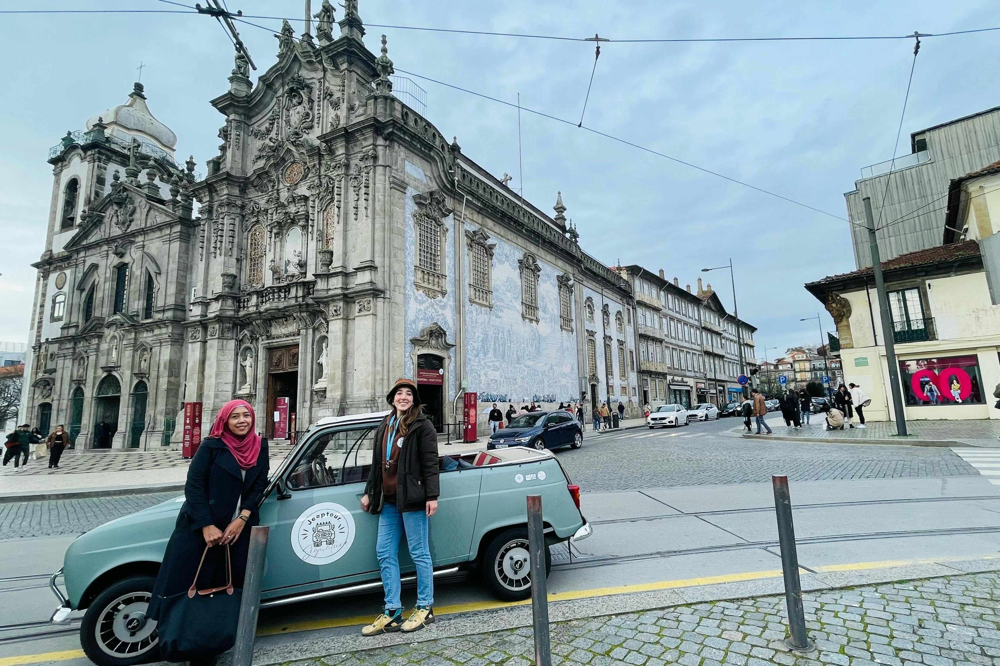 Two people standing beside a vintage blue car in front of an ornate historical church building with detailed architecture.