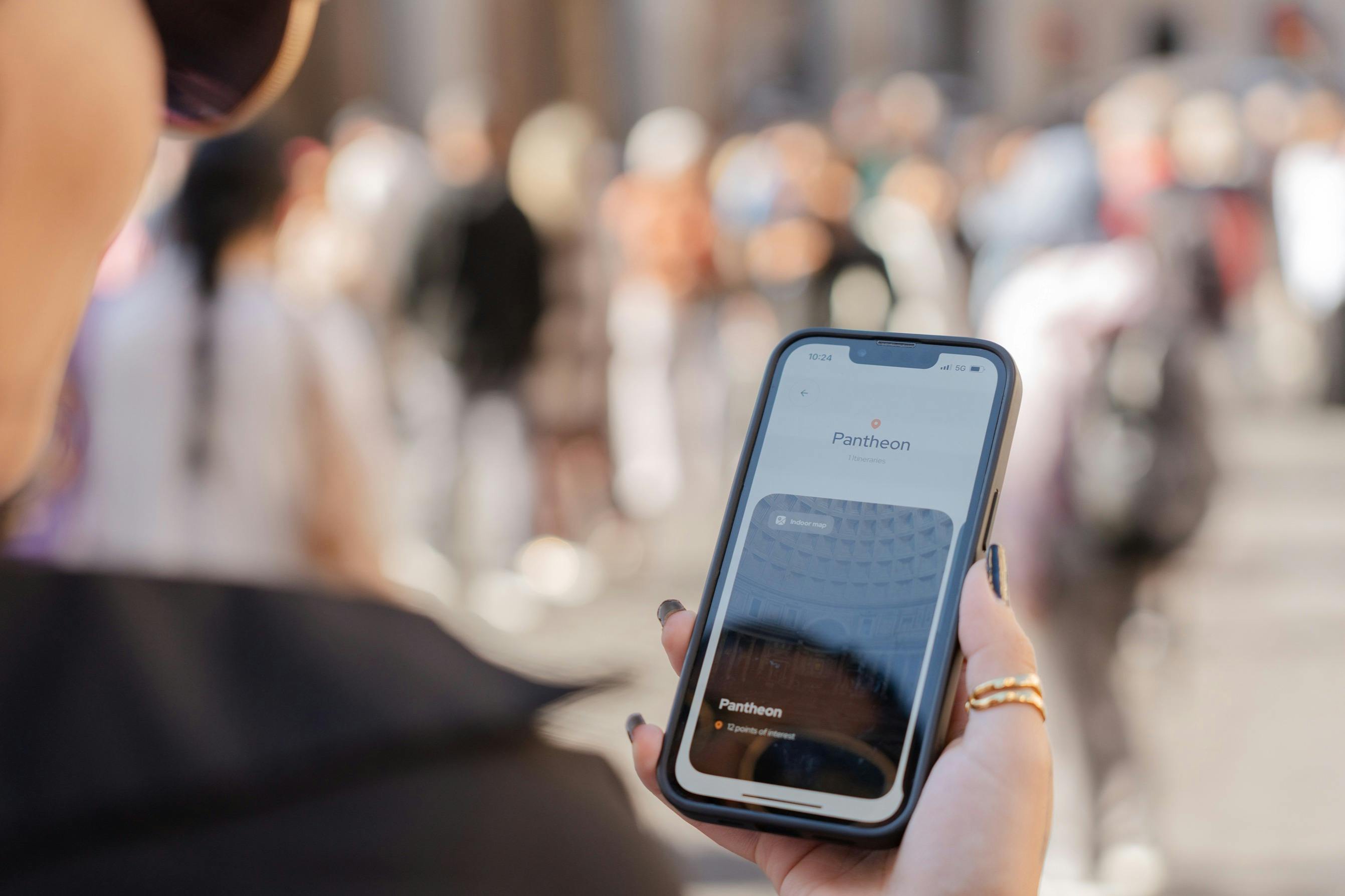 智能手机的特写镜头，在户外模糊的人群面前显示万神殿应用程序。