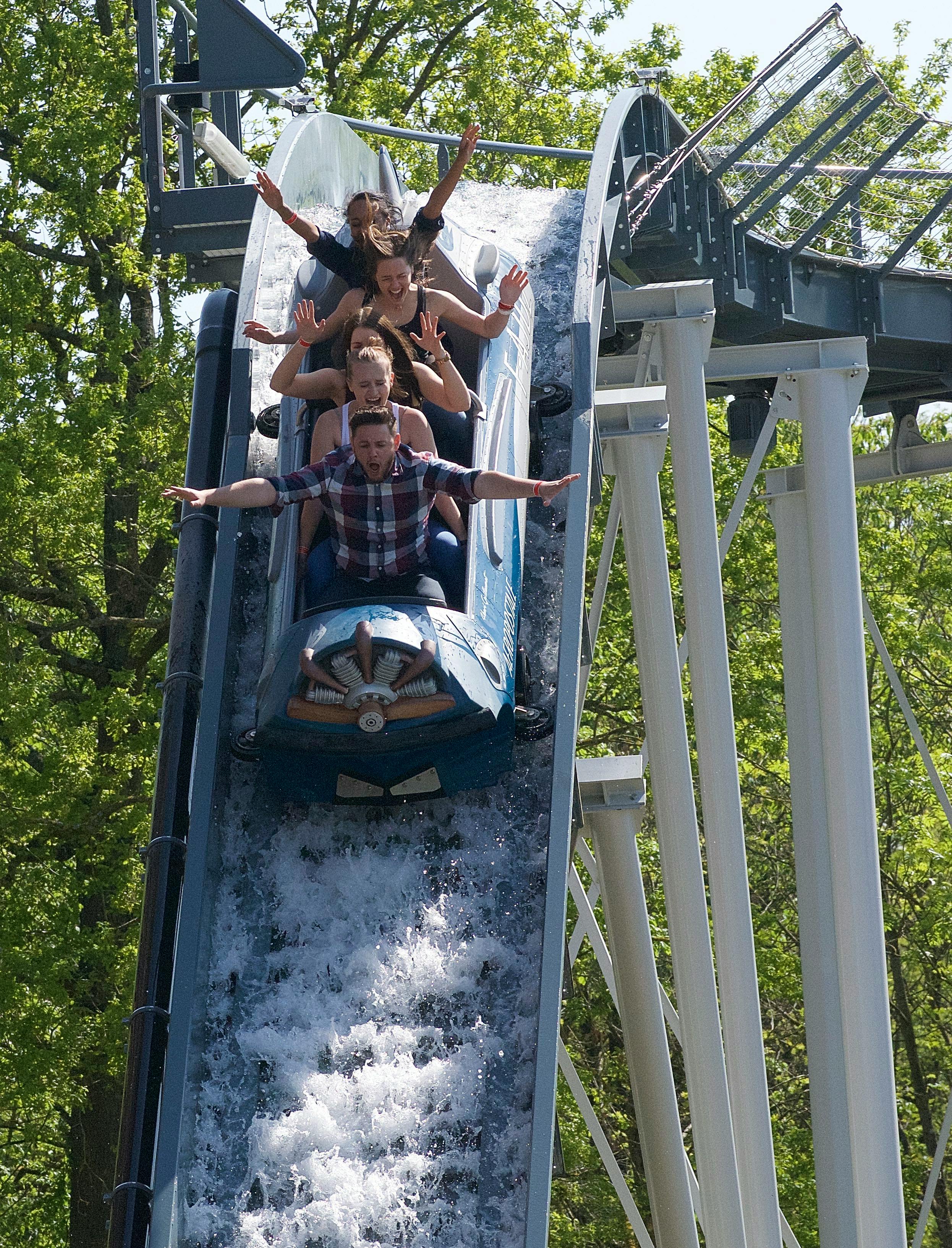 금속 구조물과 나무를 배경으로 팔을 들고 가파른 물길을 달리는 네 명의 사람들.