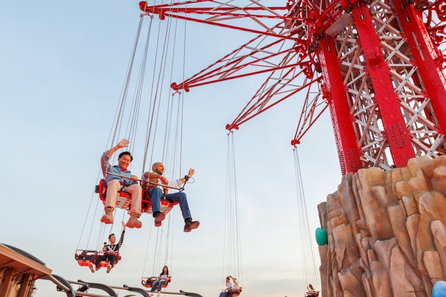 People enjoying a ride on a swing carousel against a light sky background.
