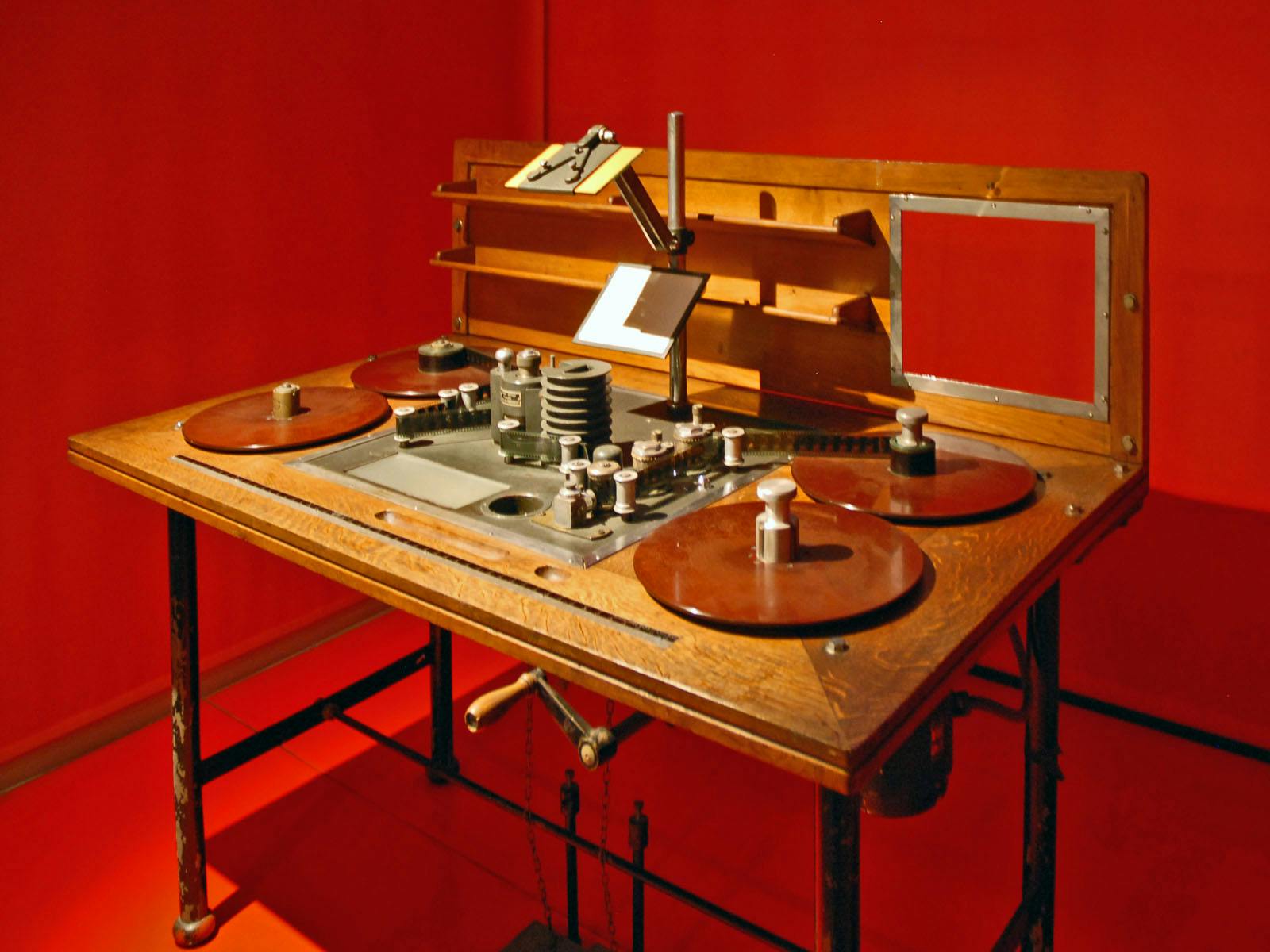 밝은 빨간색 배경에 릴, 스풀, 손잡이 및 중앙 보기 영역이 있는 빈티지 필름 편집 테이블입니다.