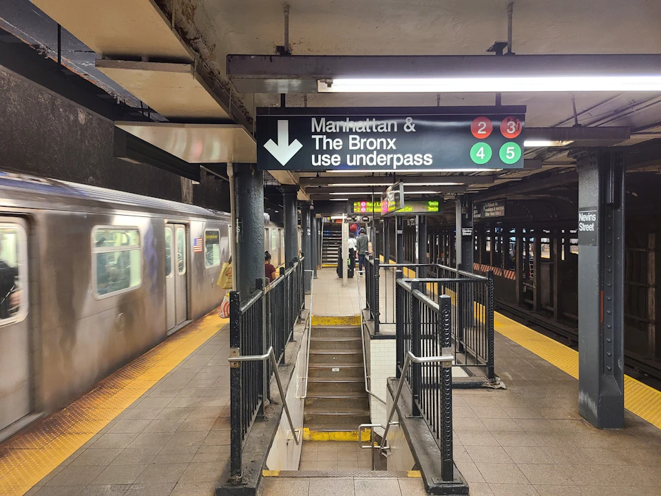 A subway station with a sign directing passengers to use the underpass for Manhattan and Bronx-bound trains on lines 2, 3, 4, and 5.