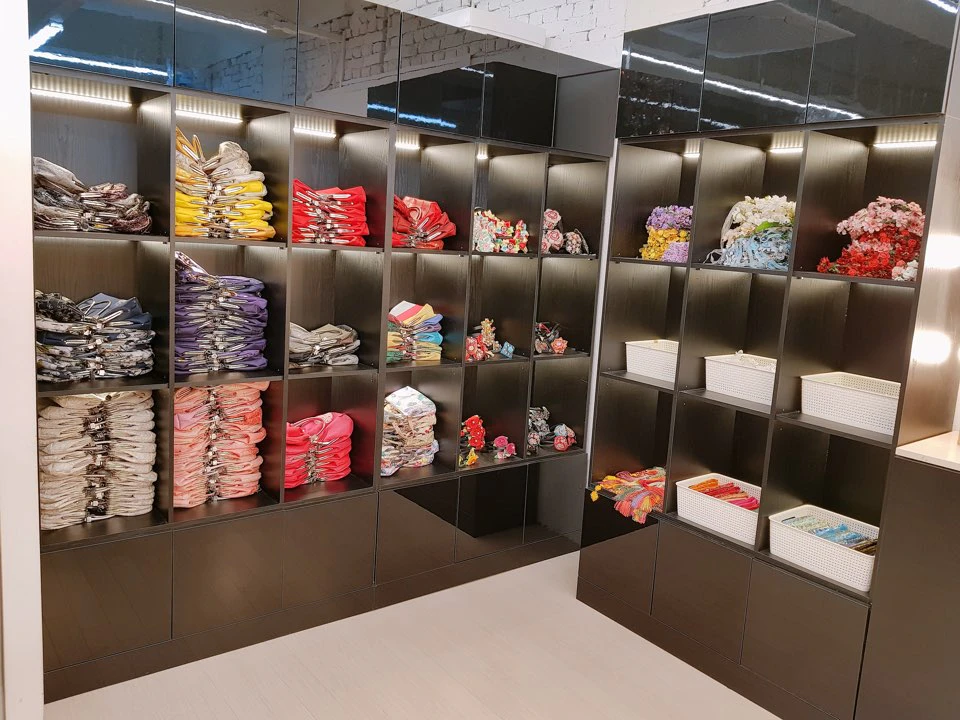 A store display with shelves holding neatly arranged colorful clothing and white storage bins in a modern setting.