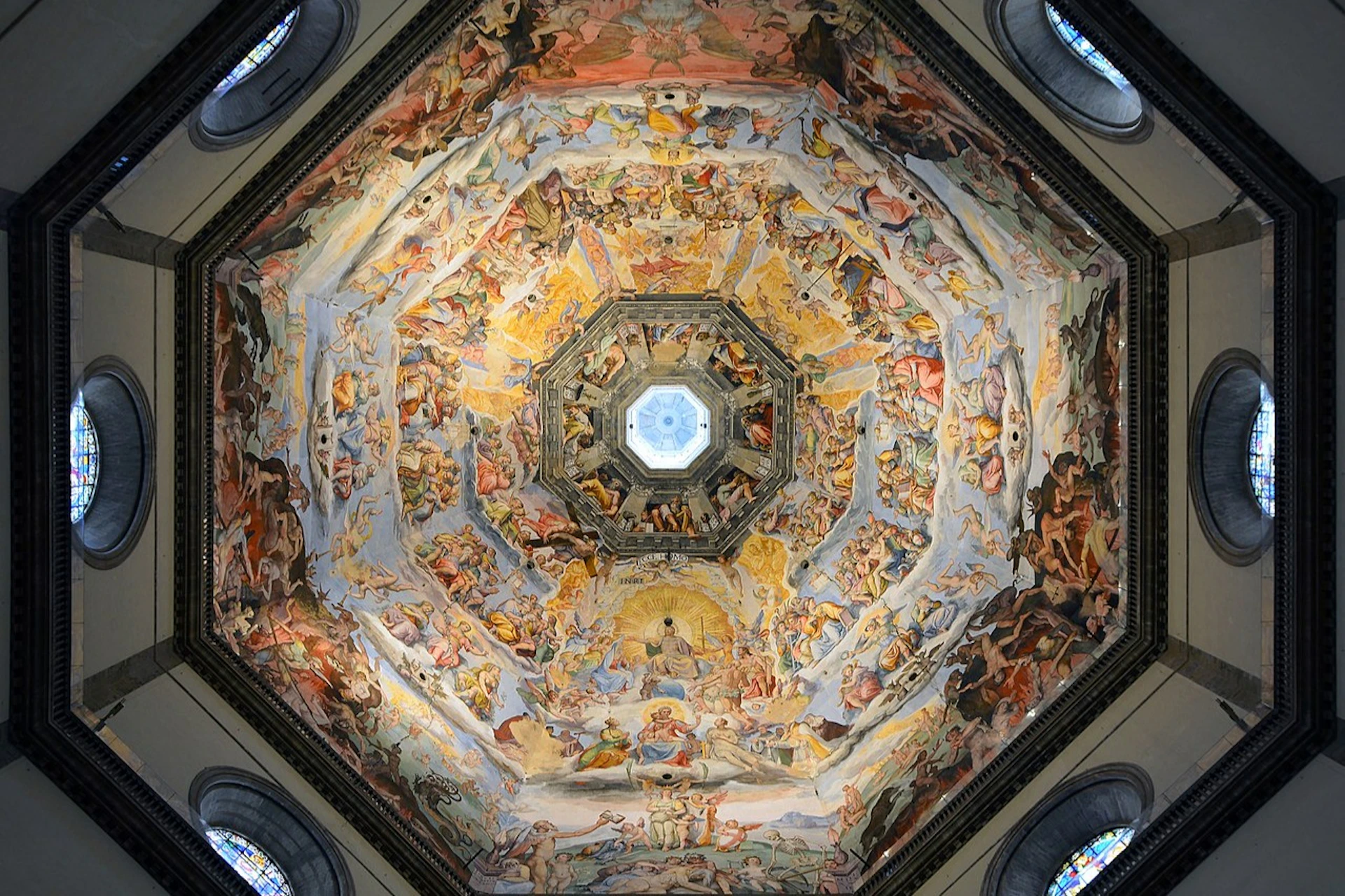 A painted dome ceiling with intricate Renaissance artwork depicting religious and mythological scenes, centered around a skylight.