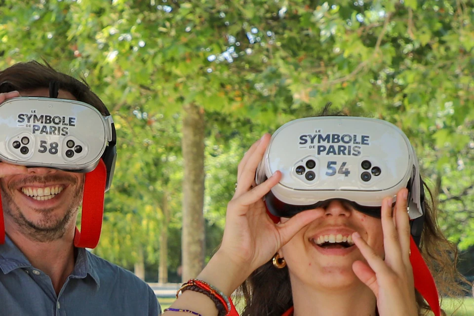 Four people outdoors wearing virtual reality headsets, standing near a tree, with a sunny park background.