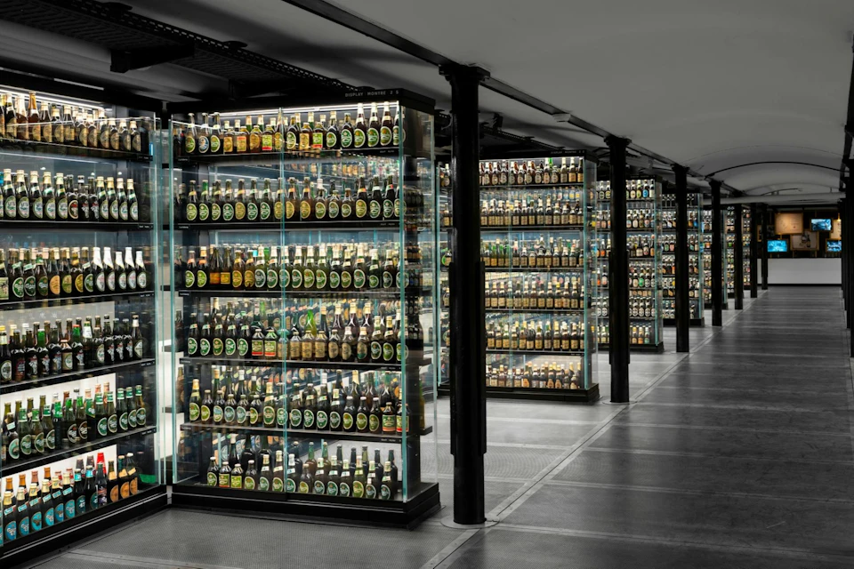 Glass display cases filled with numerous bottles, arranged neatly in a well-lit, modern exhibition space.