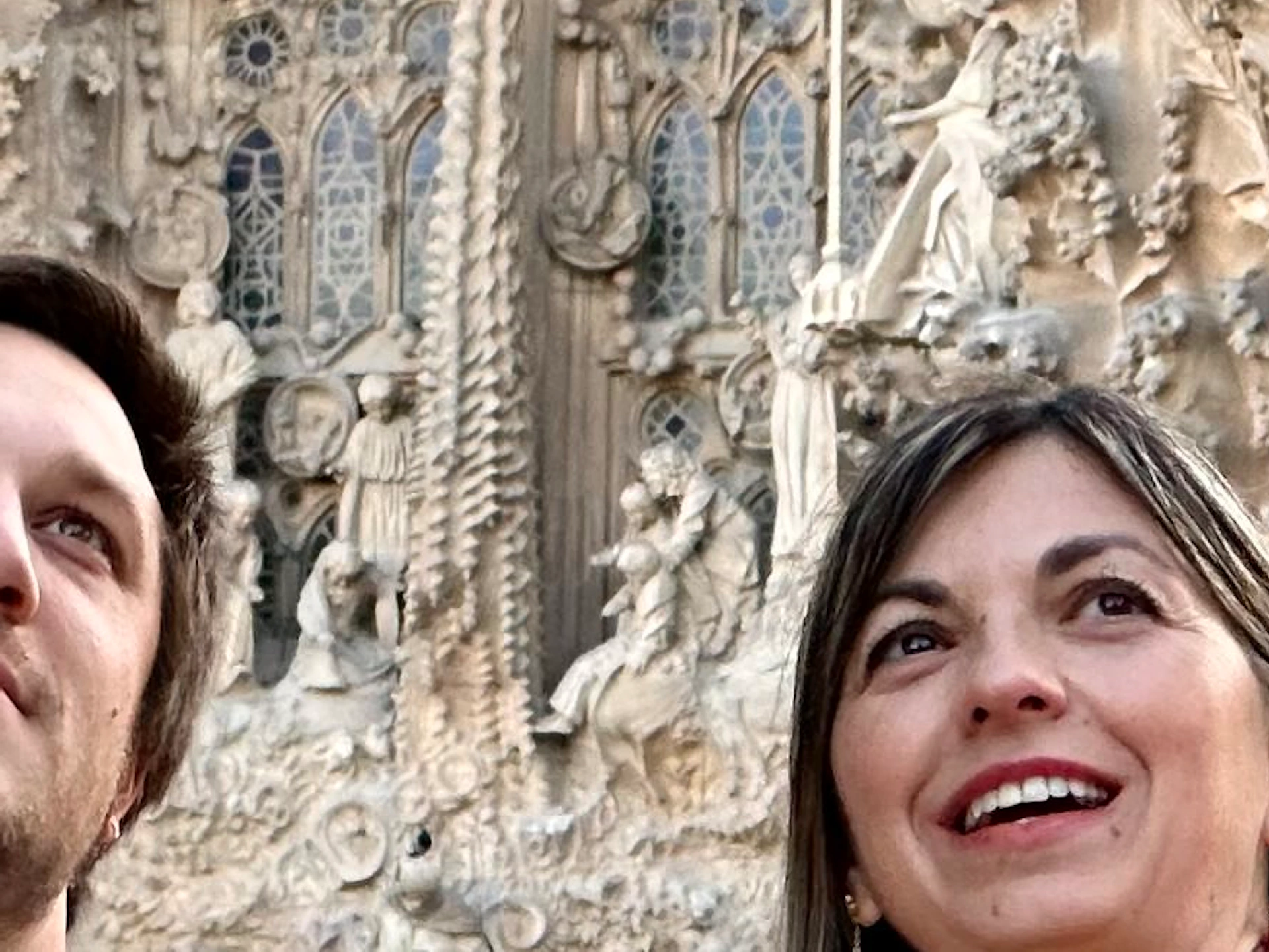 Four people standing in front of a detailed, ornate stone building facade. One woman gestures upward while others look in the same direction.