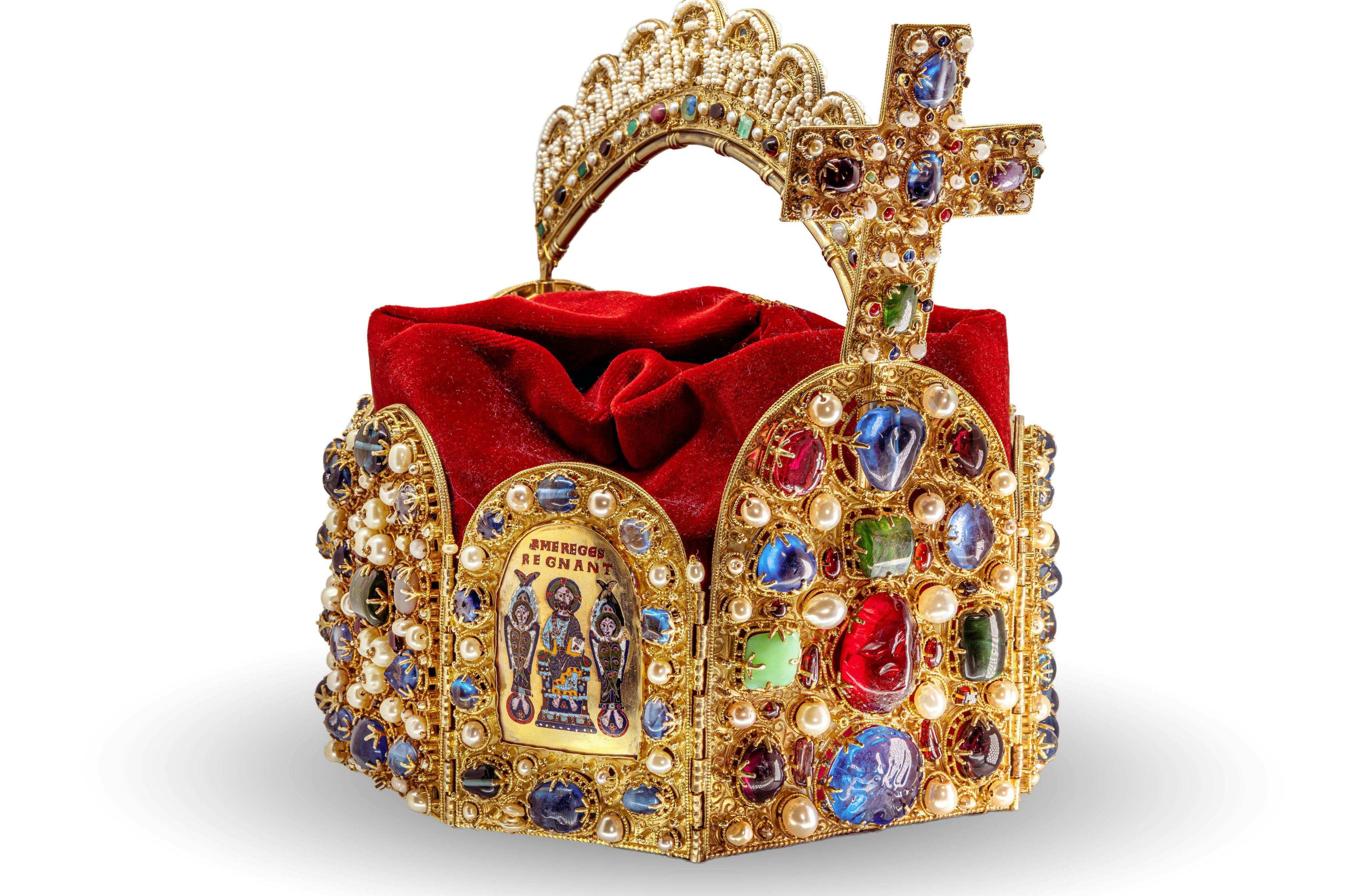 A gold, jewel-encrusted crown with a cross, featuring intricate designs and religious imagery, filled with red fabric inside.