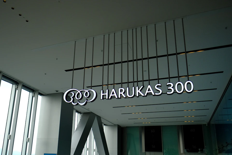 Indoor area with a large sign reading "HARUKAS 300" in white letters against a modern ceiling with vertical lines.