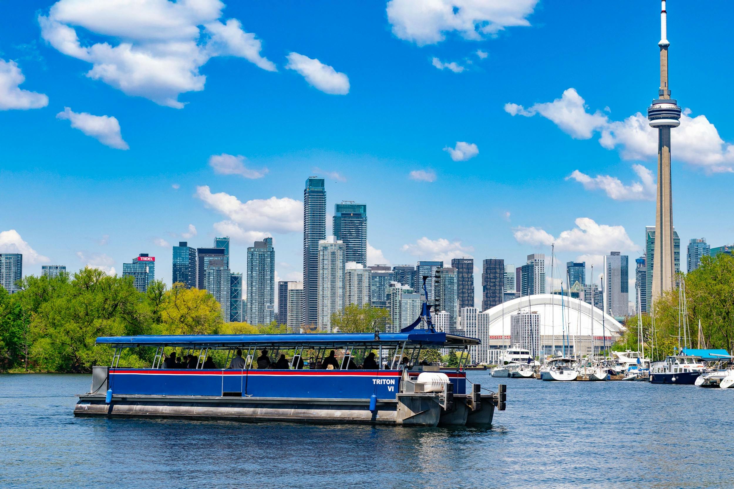 蓝天下的水上小船，背景是高层建筑的天际线。 还可以看到树木和游艇。