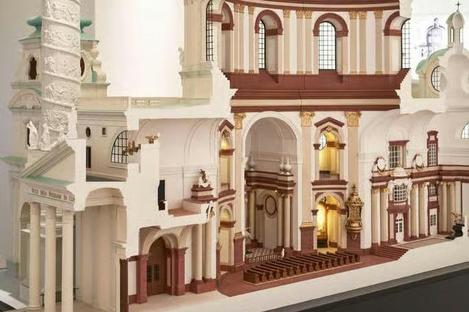 A detailed architectural model of a baroque-style church interior, showing arches, columns, and seating areas.
