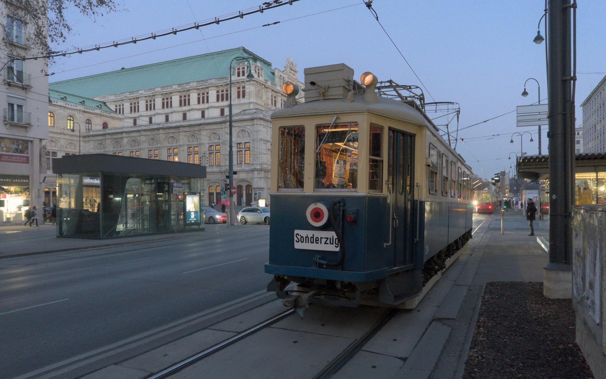 En vintage spårvagn märkt "Sonderzug" på stadsspår. En historisk byggnad med grönt tak ligger i bakgrunden.