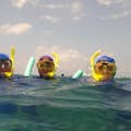 三名浮潜者带着他们的设备，安静地休息，在水下探索中捕捉放松的精髓。