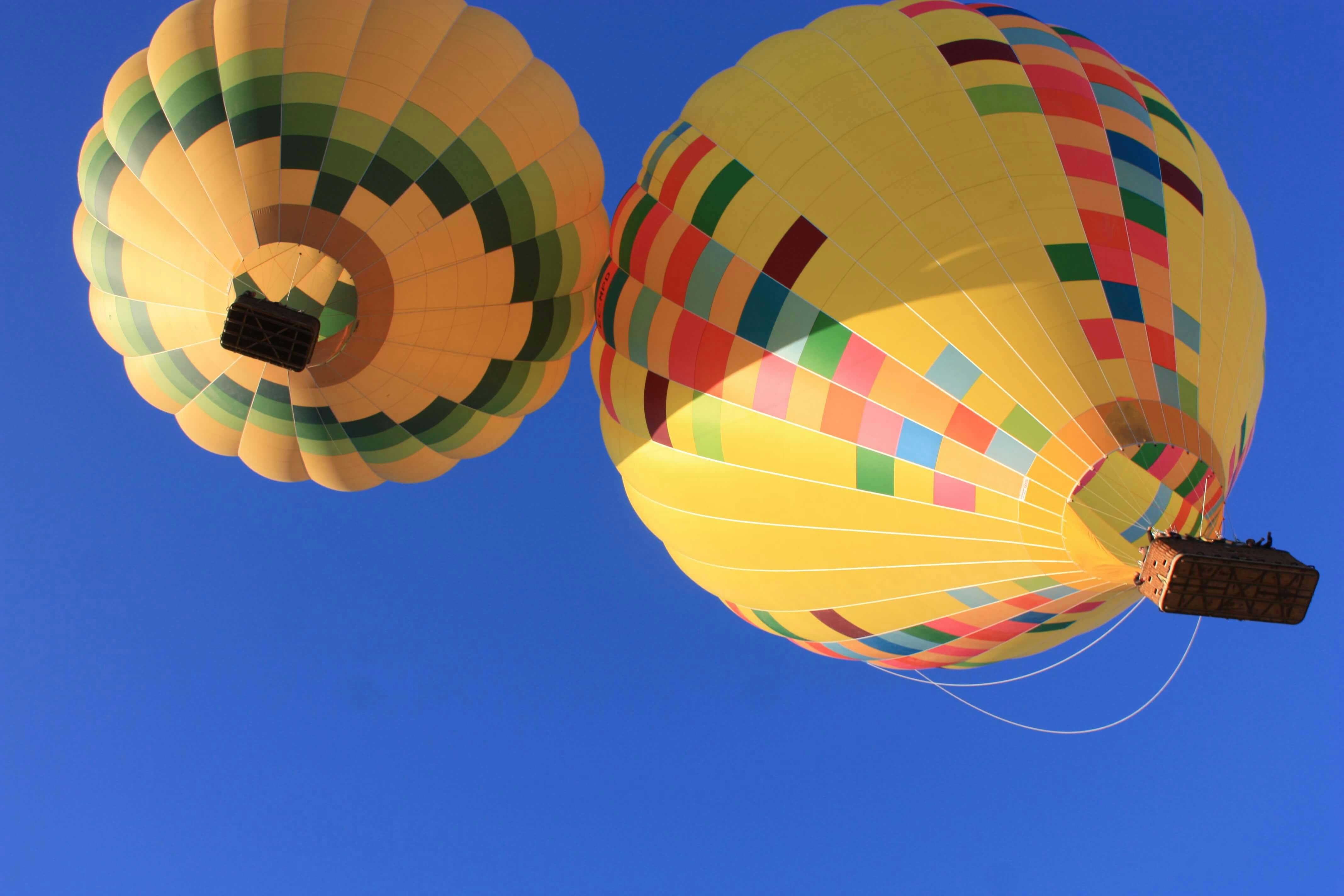 两个五颜六色的拼凑设计热气球在晴朗的蓝天下升起。
