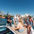 Pessoas curtindo o passeio de barco no porto de Sydney e tirando fotos dos ícones do porto ao fundo