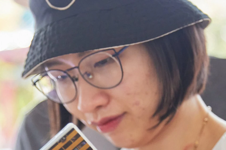 Two people wearing glasses and hats look at a brochure or magazine titled "WALKERS," with blurred, leafy background.