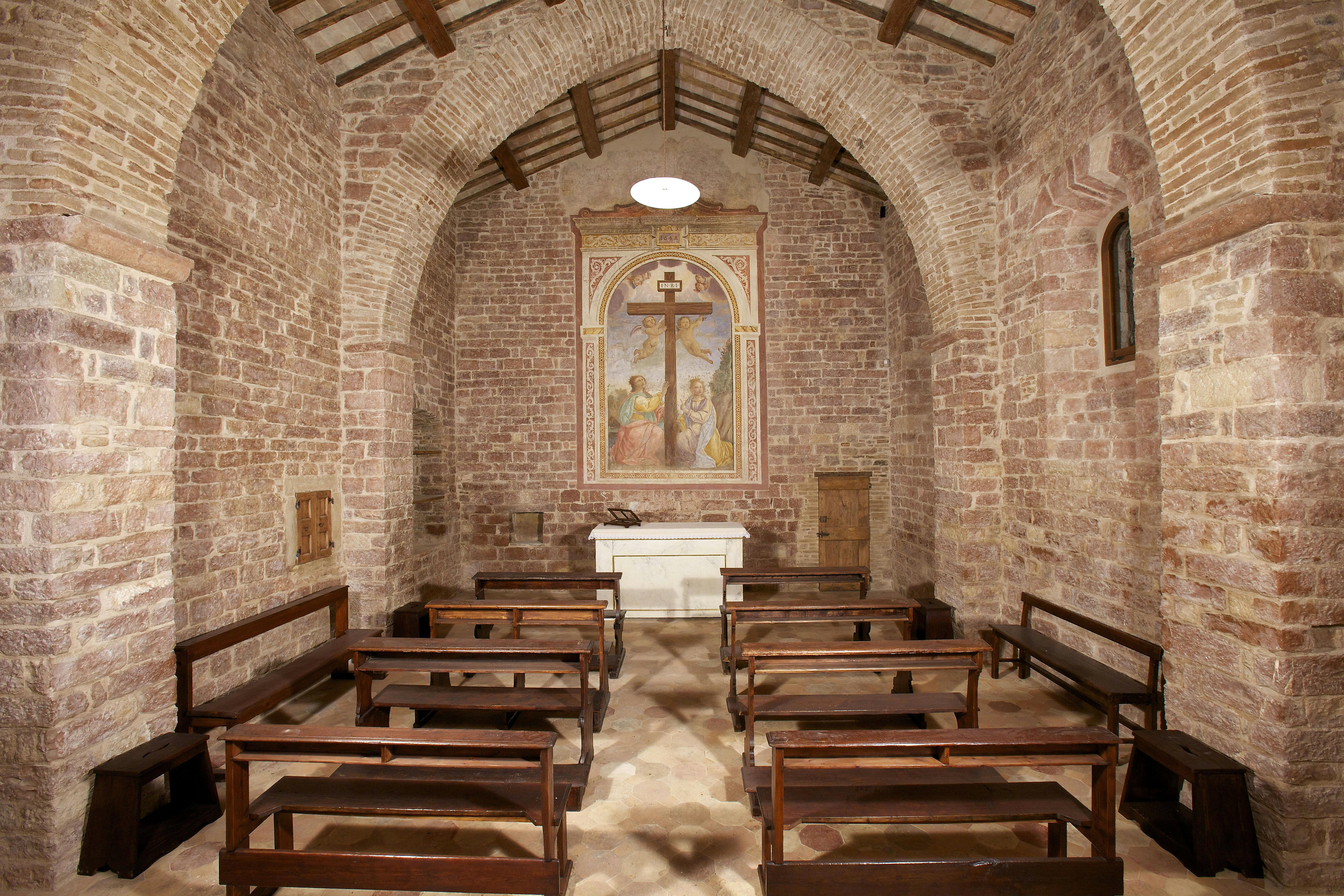 小礼拜堂，石墙，木制长凳，白色祭坛后面的十字架画。