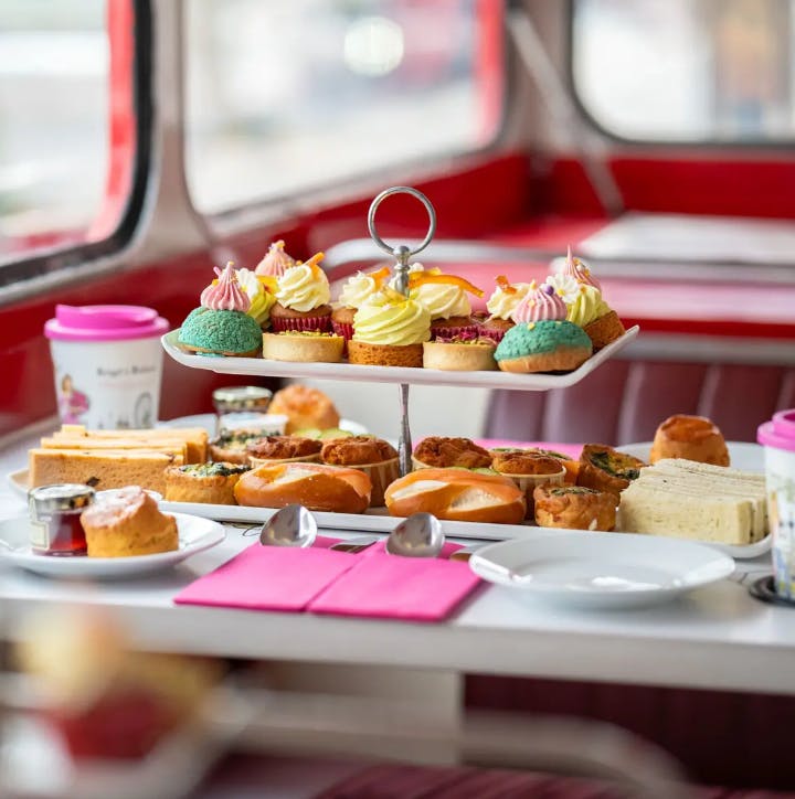 A tiered tray with assorted pastries and sandwiches on a table, inside a retro-styled red diner.