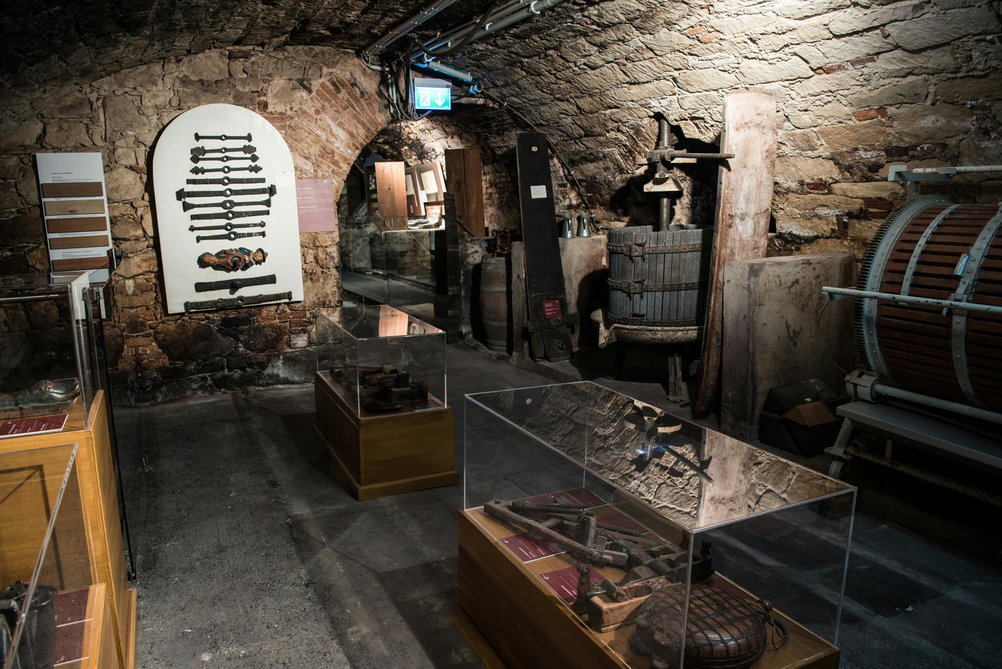 Το ιστορικό μουσείο εκτίθεται σε ένα αμυδρά φωτισμένο πέτρινο κελάρι, με παλιά εργαλεία, μηχανήματα και προθήκες με αντικείμενα.