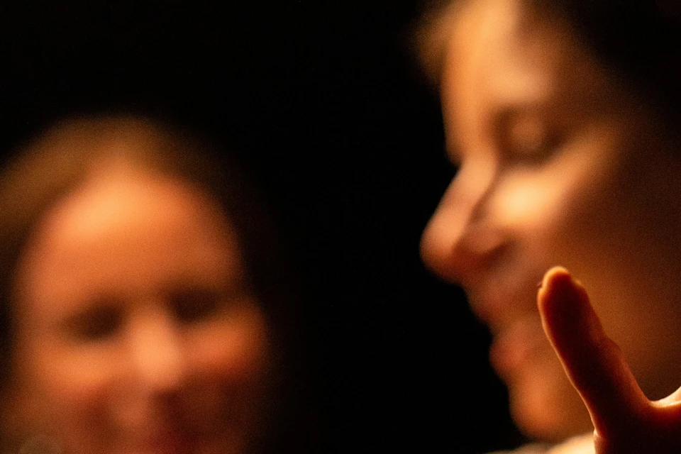 Two women move cautiously through the darkness.