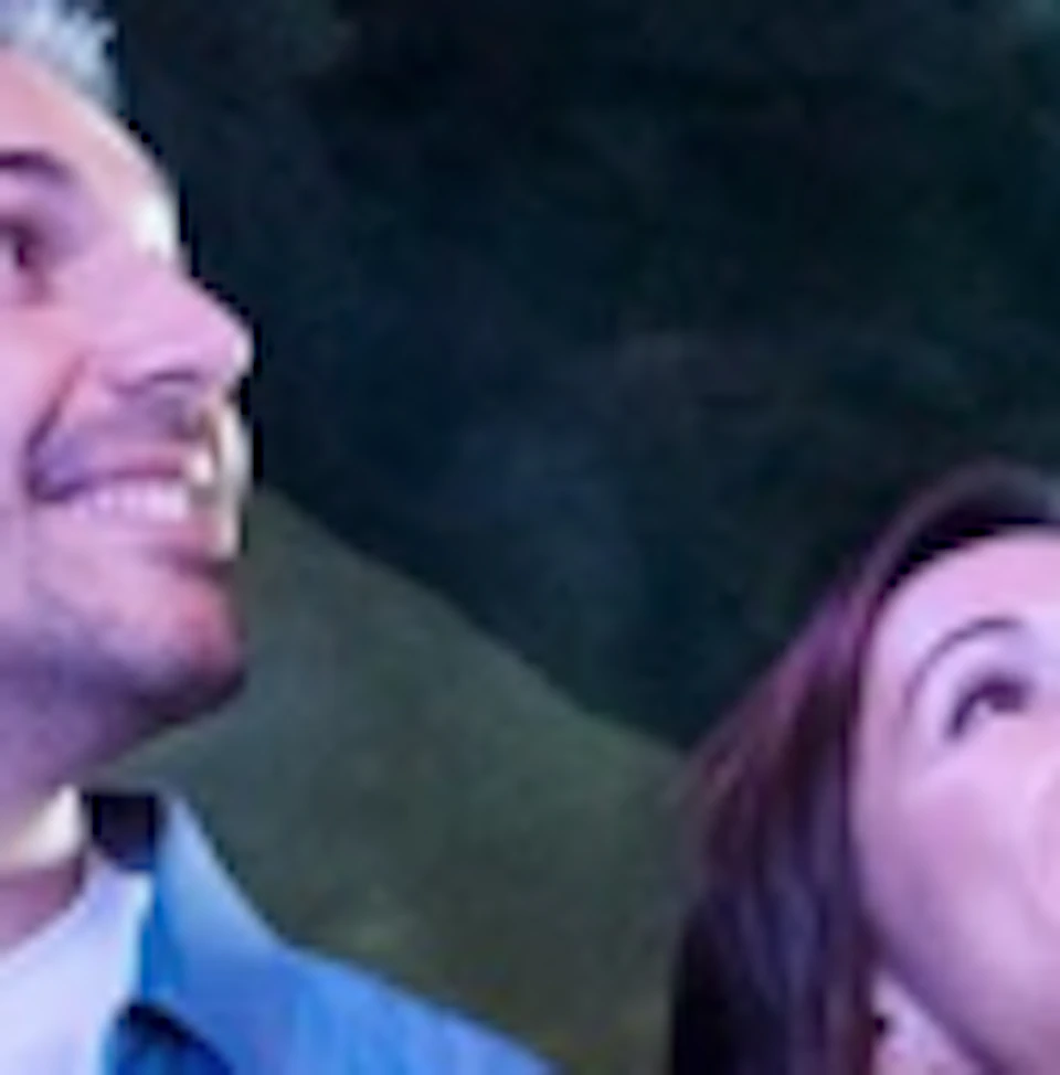 A couple walks through an underwater tunnel in an aquarium, surrounded by various sea creatures swimming above.