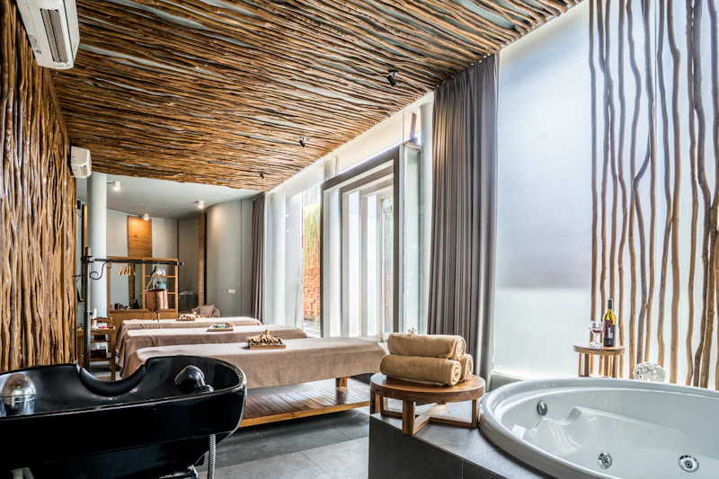 A modern spa room with massage tables, a circular hot tub, and a ceiling with a wooden branch design.