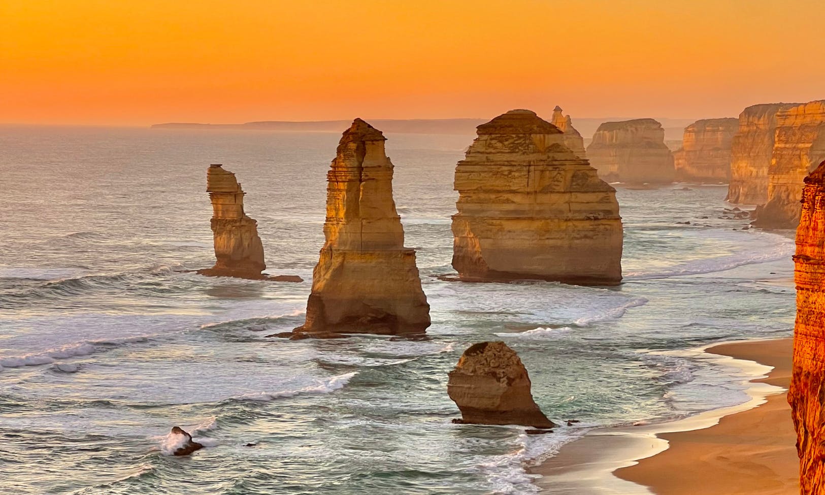 沿着海岸线从海浪中出现的十二使徒岩层的日落景观。
