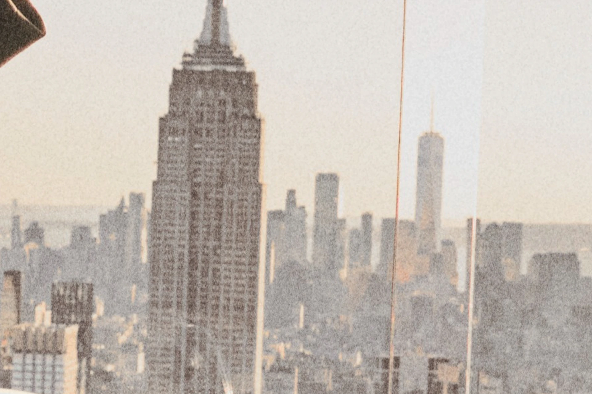 A woman and a man stand on an observation deck overlooking a city skyline, with a viewing telescope in the foreground.