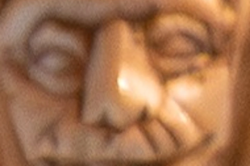 Intricately carved ivory sculpture featuring a figure in traditional attire on top, with detailed motifs and faces below.