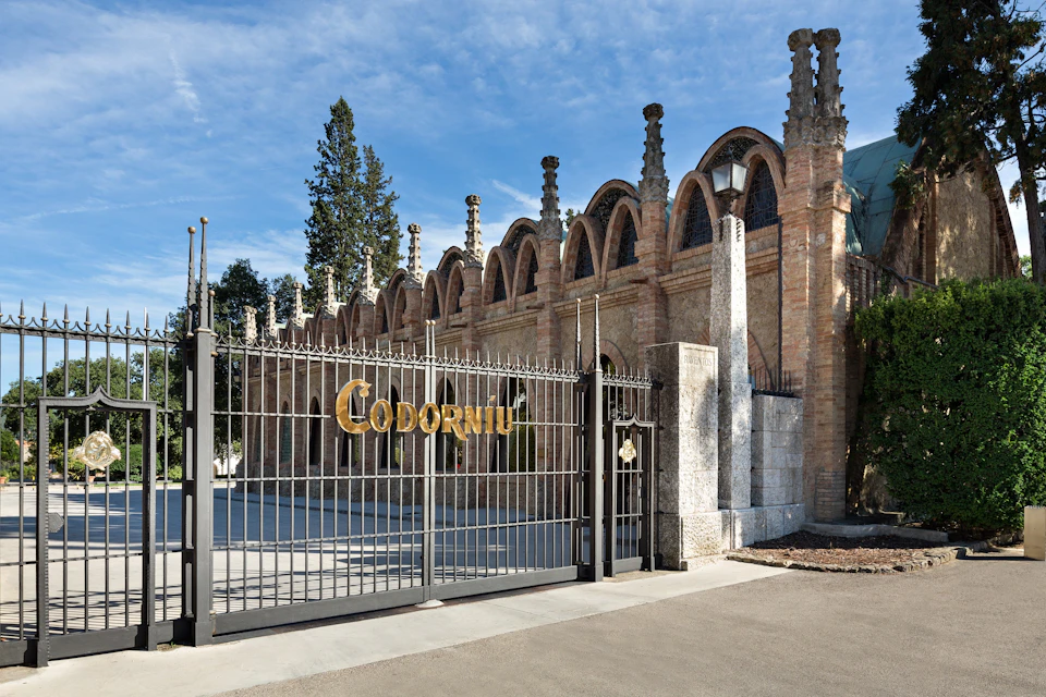 A historic building with arched windows and a gated entrance bearing the name 'Codorníu' under a clear blue sky.