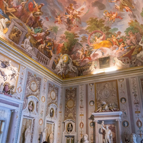 Sala ornata con affreschi dettagliati sulle pareti e sul soffitto che raffigurano scene mitologiche, adornata con sculture e disegni intricati.
