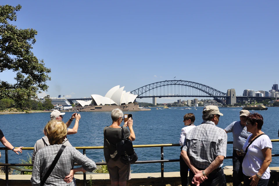 The bus tour group at Mrs Macquaries Point. Tourists are taking pictures of the Sydney Opera House and the Harbour Bridge.