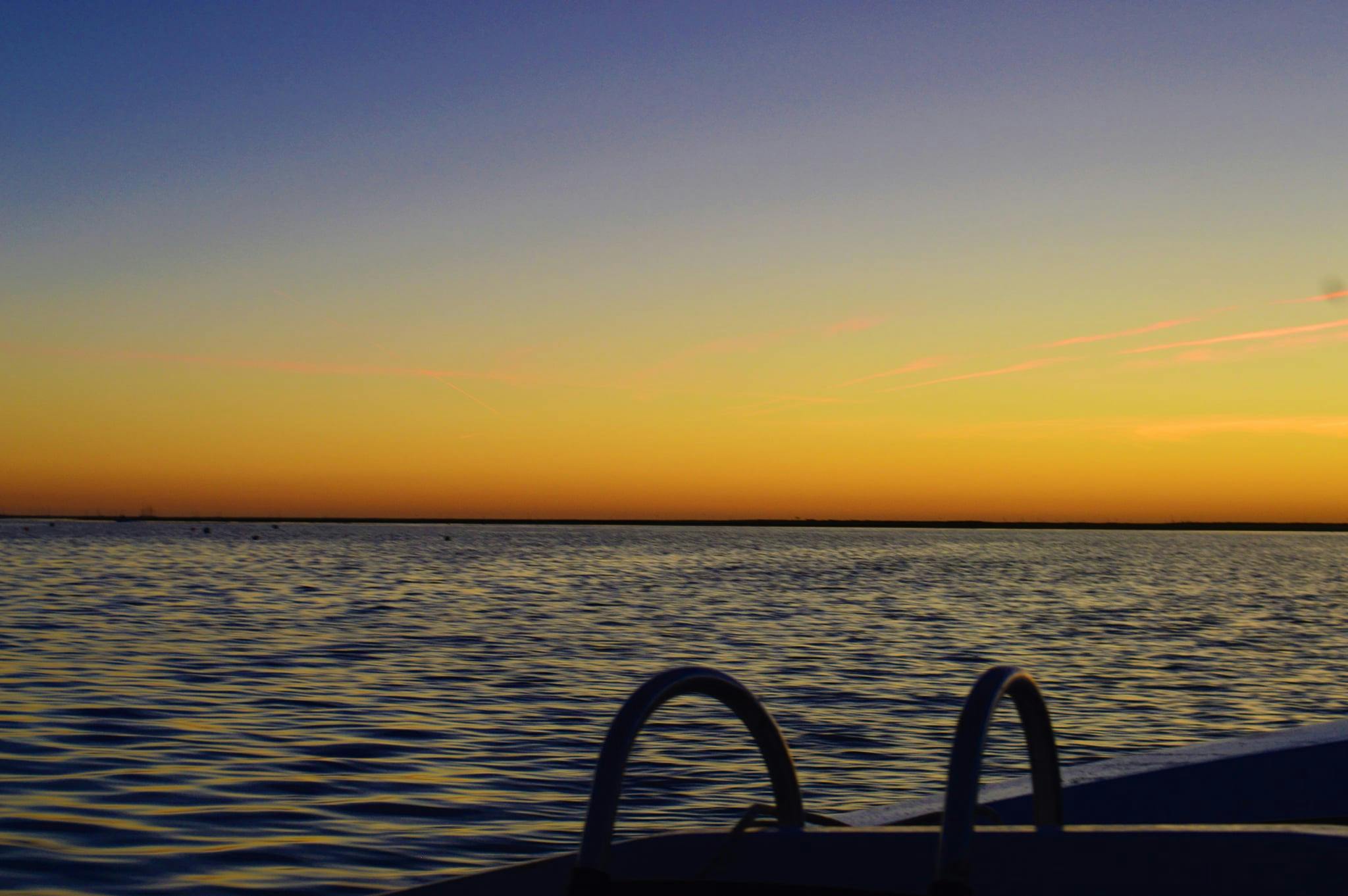 Спокойные воды на закате с красочным небом и лодочной лестницей на переднем плане.