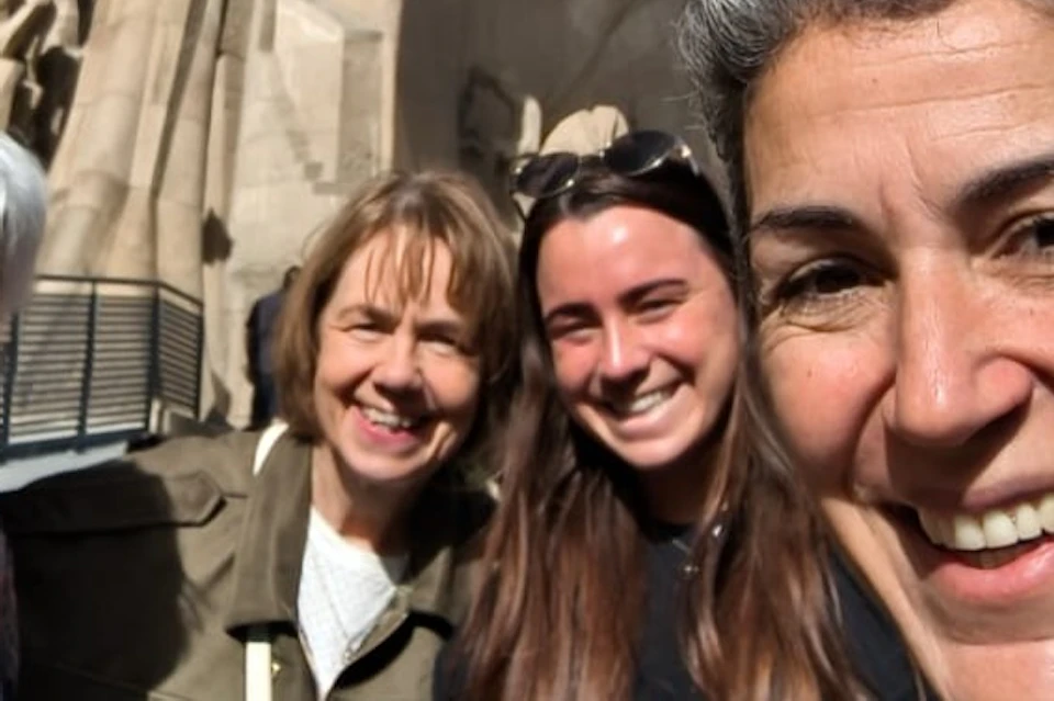 Four people smiling together in front of a large carved stone facade with statues and architectural details.