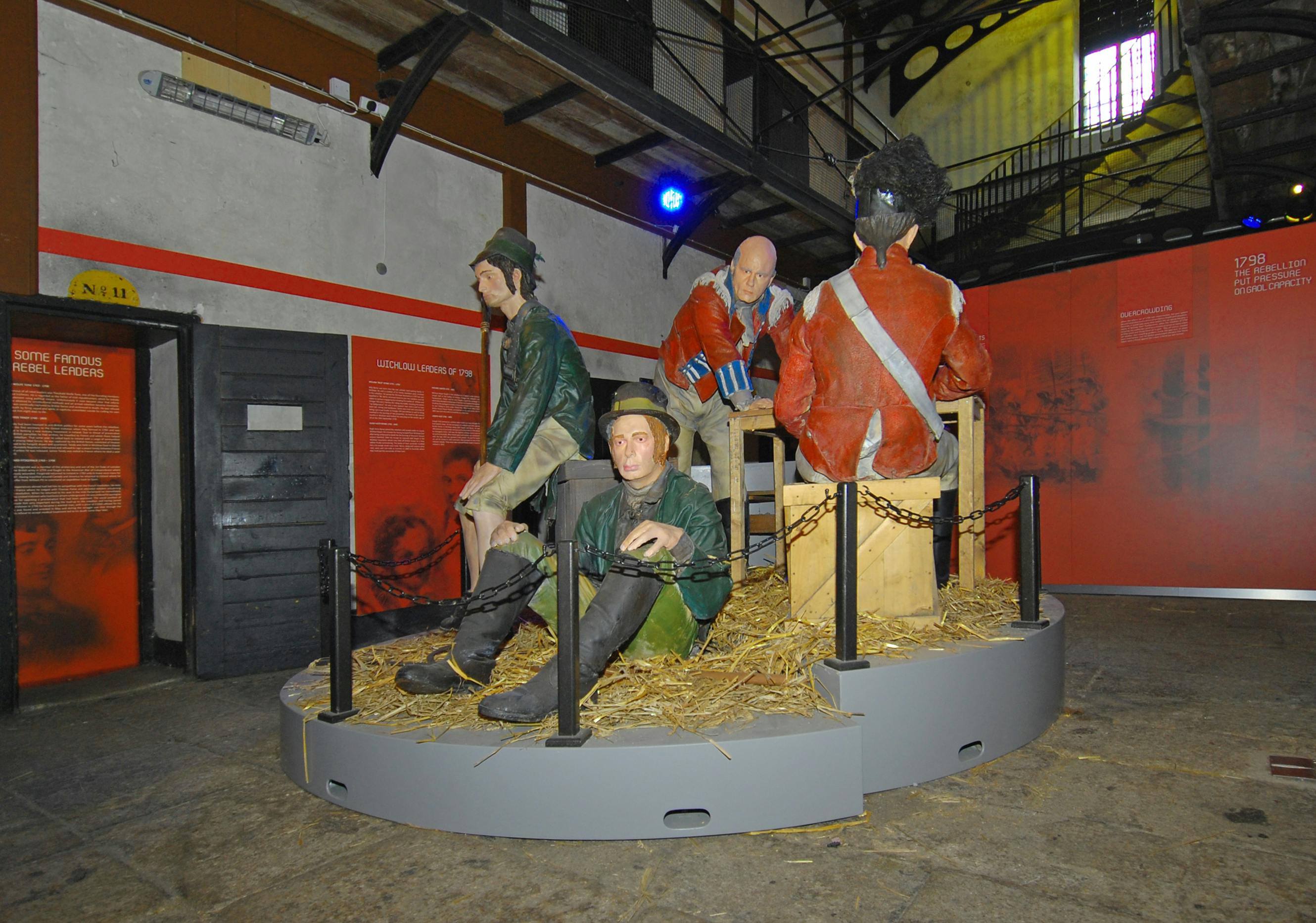 Tři sochy v životní velikosti zobrazují vojáky a vězně uvnitř muzejní expozice s jedním britským červenokabátníkem, který stojí na stráži.