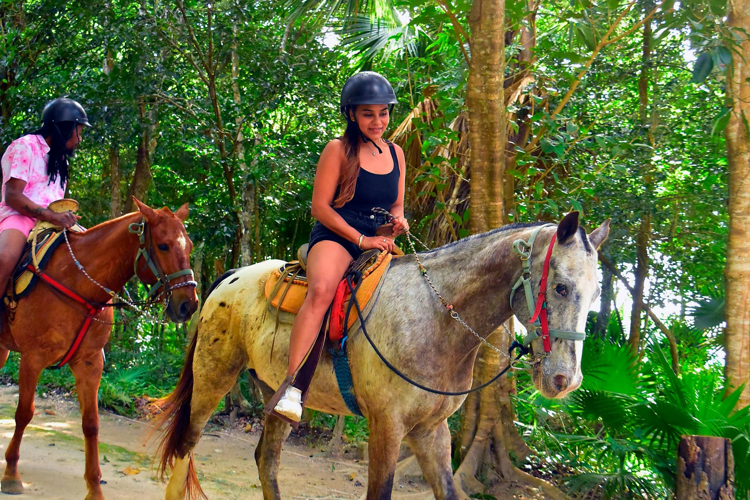 Ung dame, der rider på en hest i junglen