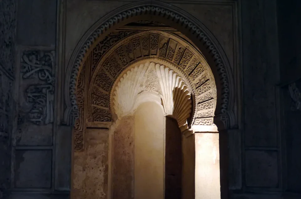 An intricately decorated archway with detailed carvings and patterns, illuminated by light from one side.
