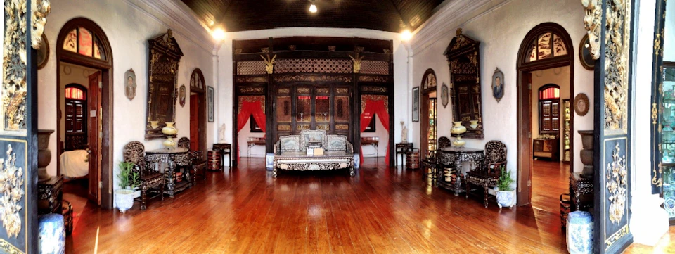 An ornate room with wooden flooring, intricate furniture, red curtains, and decorative elements on the walls and ceilings.